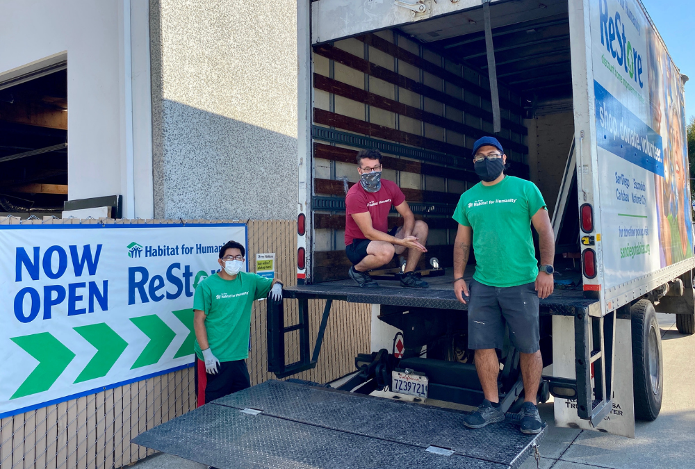 Three masked ReStore drivers posing with delivery truck used for residential donation pickups