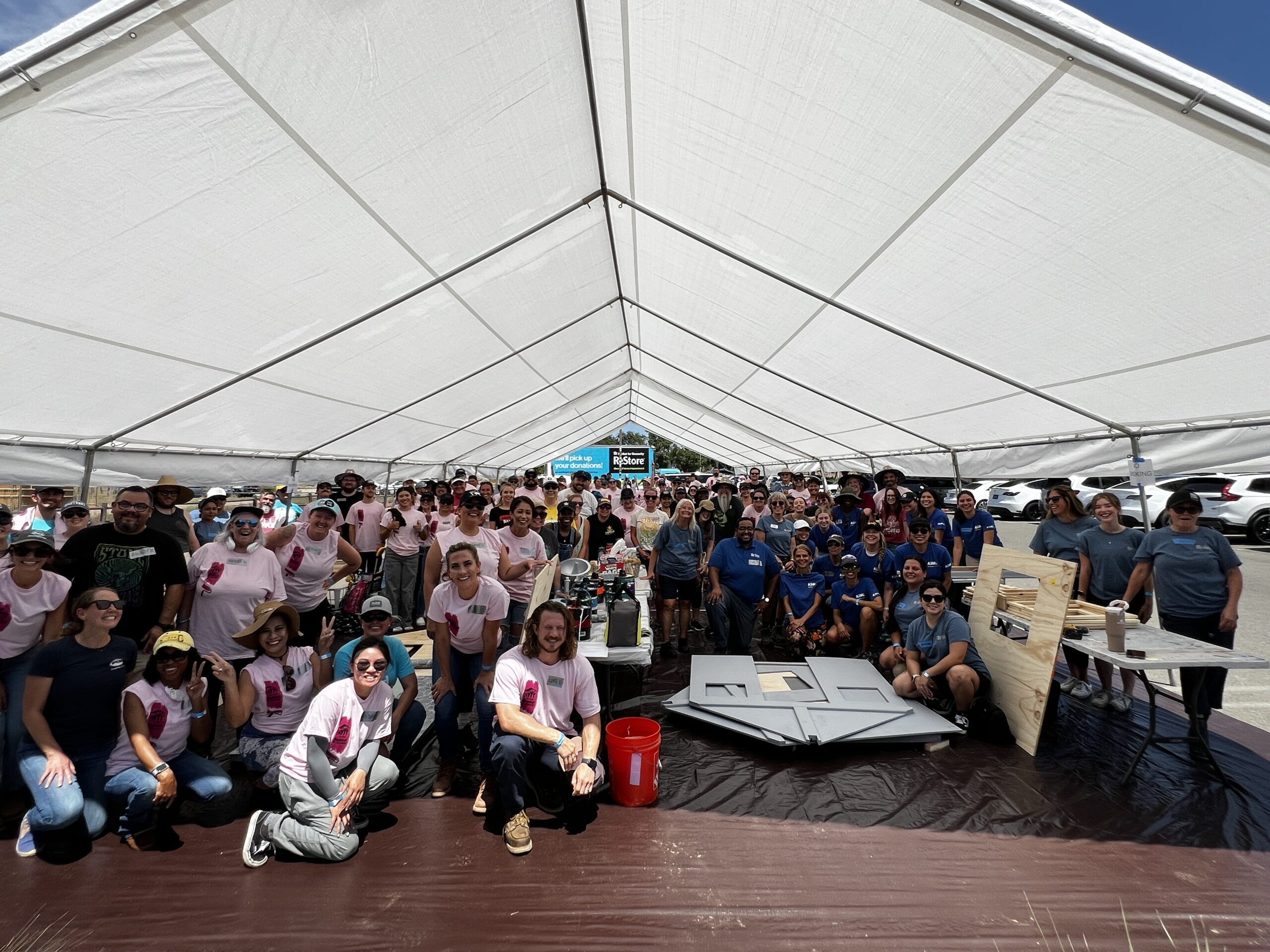 20250821_191118871_iOS (1) Women Build 2025 - Group photo under a large white tent.